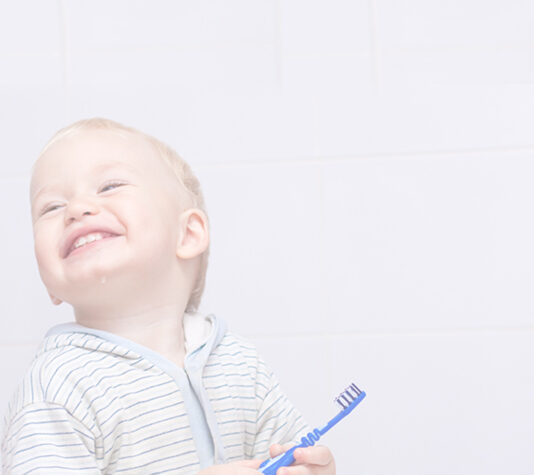 Child smiling and holding toothbrush